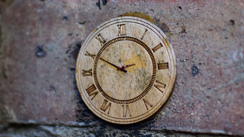 Metal analog clock on a stone wall
