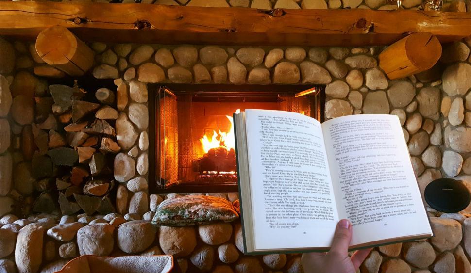 Photo of an open book in front of a cozy fireplace