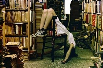 Vintage photo of a woman with sneakers leaning back in a chair in a room full of books