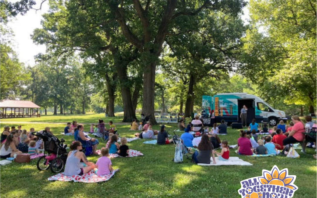 Photo of an outdoor photo of Story Time in the park, with the PPL Bookmobile. The "All Together Now" logo is in the bottom right corner.