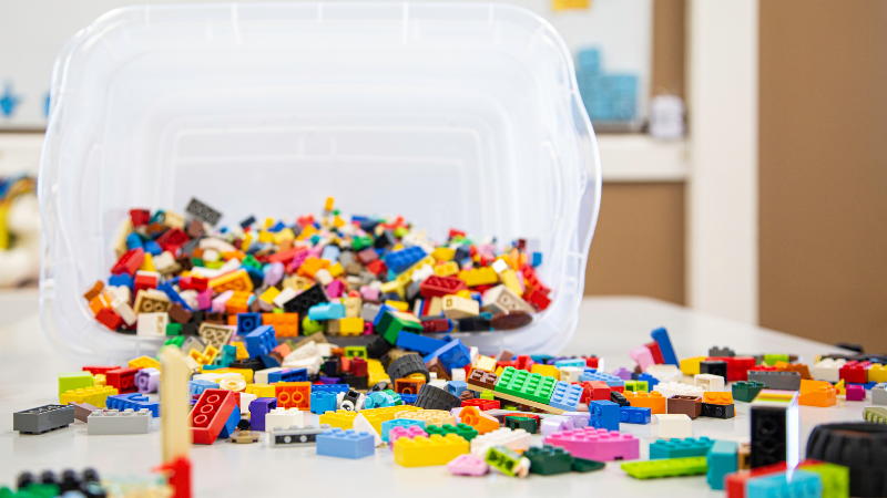 Photo of a tub of LEGOs spread across a table. Looks like fun!