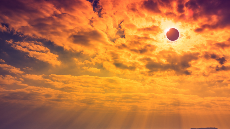 A stylized photo of a big cloudy sky with the moon eclipsing the sun.